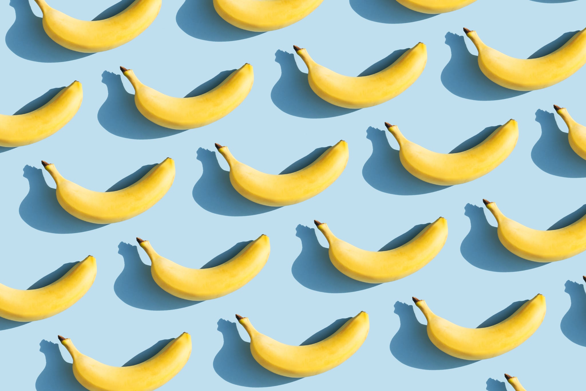 Красочный фруктовый узор из свежих желтых бананов на синем фоне с тенями.  Концепция фруктов.  Плоская планировка, вид сверху.